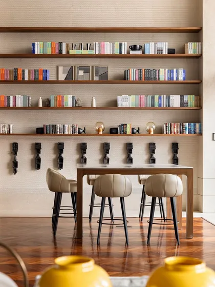 This high-top seating area against a wall of books offers a casual spot for work, reading, or a quick coffee. It's one of the many "in-between" spaces we design to support various activities and make the clubhouse feel like a true extension of home.