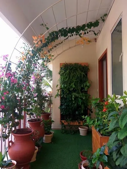 For clients who want a true garden feel, I create lush, green sanctuaries. This balcony features an arched trellis for climbing plants, a vertical garden wall for dense foliage, and a variety of terracotta planters, all on a soft artificial grass floor.