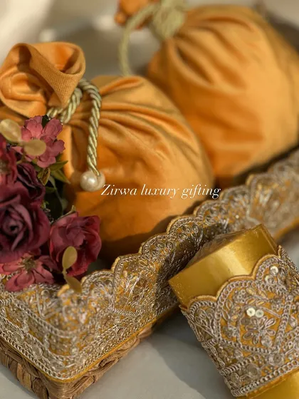 A closer look at the yellow-themed Lohri favours. The rich velvet potlis are complemented by delicate floral arrangements, creating a luxurious and elegant gift.