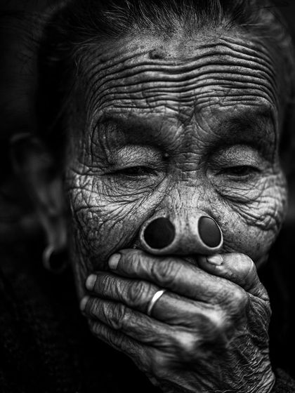 A powerful black and white portrait of an Apatani woman from Arunachal Pradesh. The texture of her wrinkled skin and the traditional nose plugs tell a story of a disappearing culture.