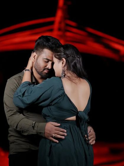 An intimate embrace against a dramatic red-lit background. The intense color and close-up pose create a passionate and moody night-time portrait.