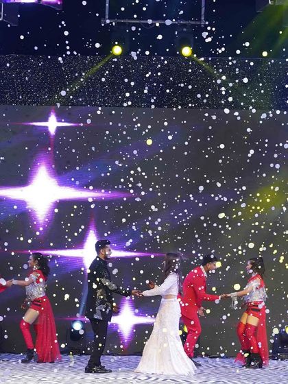 A night illuminated by love and the brightest stars. A romantic couple dance on the Sangeet stage, set against a backdrop that looks like a galaxy.