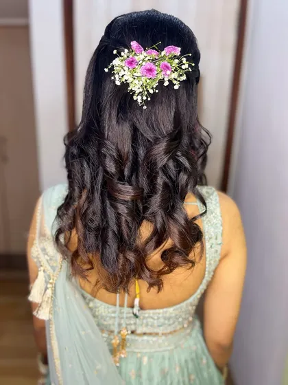 A classic half-up, half-down hairstyle with soft curls and a floral accessory. This look is perfect for the groom's sister.