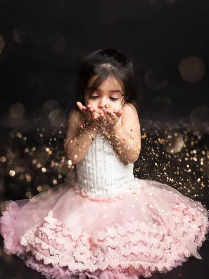 Blowing a handful of golden star glitter towards the camera. This is such a dreamy and whimsical shot, perfect for a little princess.