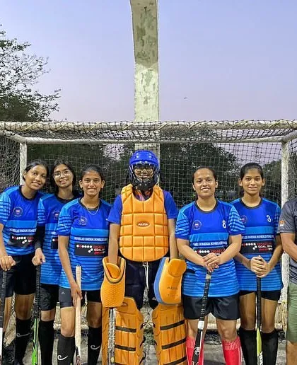 The girls' team posing for a photo with their coach and goalkeeper after a successful exhibition match.