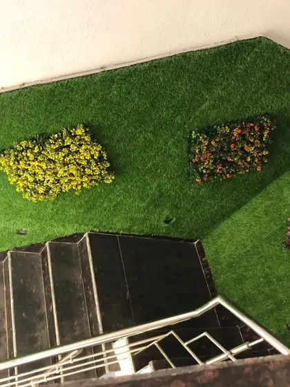 This view from the top of a staircase shows how I used artificial grass on the walls with small, colorful plant clusters to add visual interest. It's an unconventional and creative approach to wall decor.