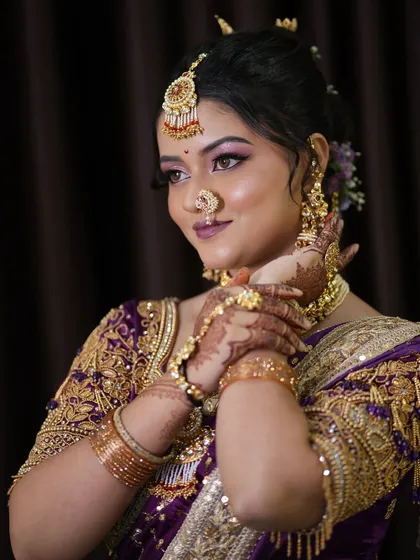 A beautiful portrait of a Maharashtrian bride in a purple saree, showcasing the intricate details of the makeup and jewelry.