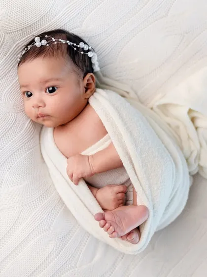 A classic newborn pose, with the baby gently wrapped and posed on a soft, textured blanket. Safety and comfort are always our top priorities.