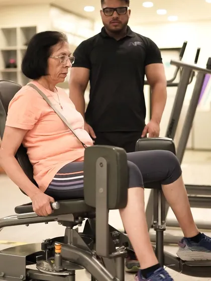 Fitness is for everyone, at any age. Here, one of our expert trainers provides personalized guidance to a member, ensuring her form is safe and effective on the hip adductor machine.