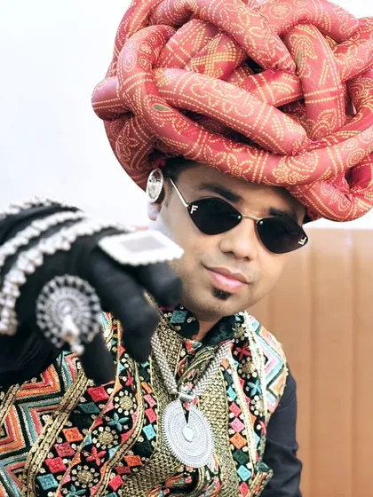 Pointing to the crowd, inviting them to join the celebration. The large, intricate turban was a key part of this memorable look.