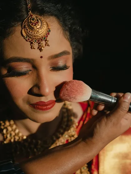 The final touches. This shot shows the application of blush, adding a healthy and natural flush to her cheeks.