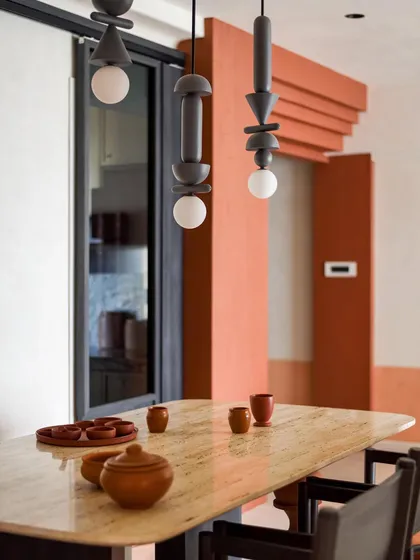 A close-up of the custom light fixtures and the travertine dining table. The design is all about celebrating natural materials and handcrafted details.