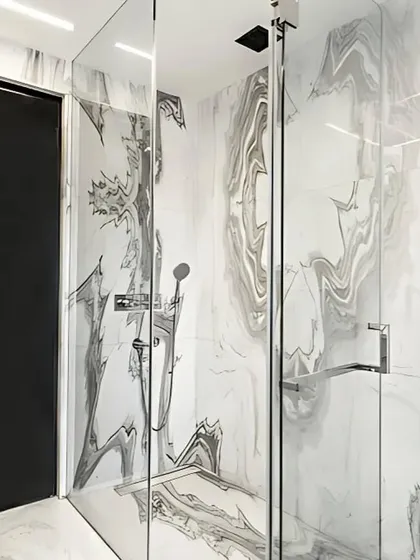 Luxury is in the details. For this executive bathroom, we used bookmatched Satvario Gold stone slabs to create a seamless, dramatic pattern in the shower enclosure. This technique turns natural stone into a work of art, demonstrating our commitment to high-end materials and meticulous craftsmanship in bathroom design.