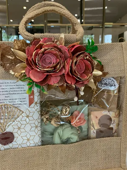 The complete "Welcome to the family" hamper in a sustainable jute bag with a clear window. The arrangement showcases a mix of modern and traditional elements.