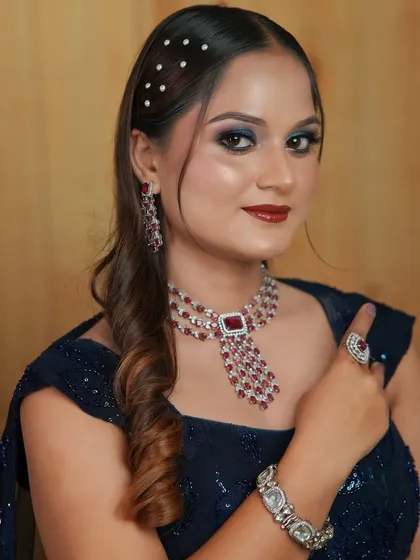 A close-up portrait of the cocktail look, highlighting the dramatic eye makeup and the ruby and diamond jewelry.