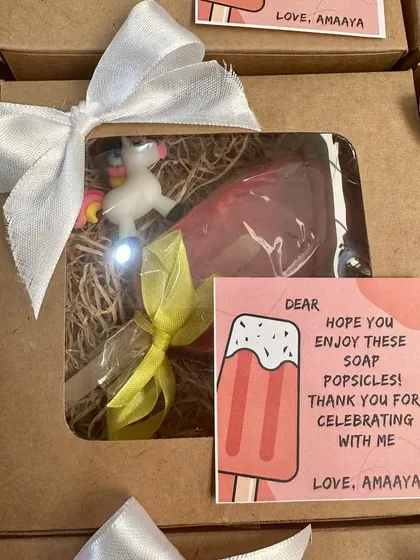 A fun popsicle-themed birthday return gift, including a personalized initial soap and a unicorn keychain.