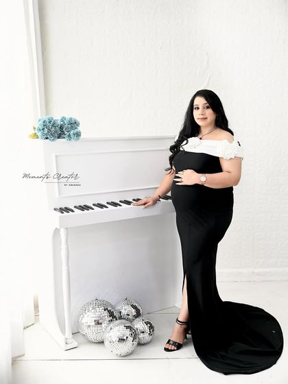 A classic and elegant solo portrait by the white piano. The simple black gown and bright, clean background create a timeless and sophisticated look.