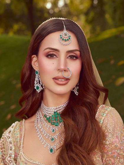 A close up on the soft glam makeup. The eyes are defined with soft pinks and a subtle liner, paired with a natural lip color to complement the emerald jewelry.