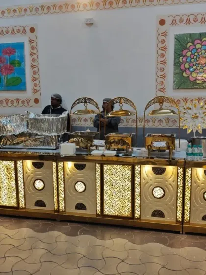 Our staff is ready to serve at a beautifully decorated live food counter. The traditional artwork in the background complements our premium setup for a wedding event.