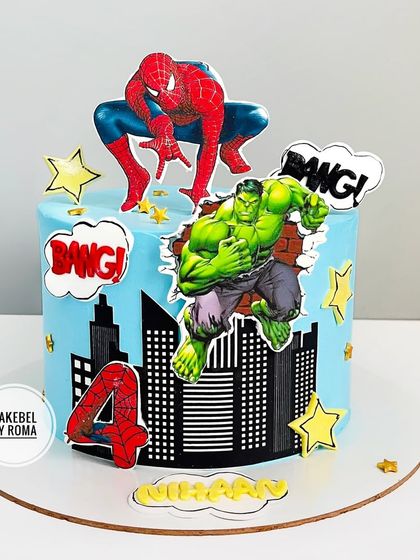 A powerful superhero cake featuring both Spider-Man and the Hulk against a city backdrop. The design is full of energy with "BANG!" comic book effects.