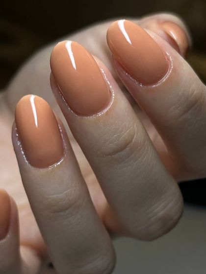 A warm, caramel-toned nude polish on medium-length oval nails. This color is a versatile and sophisticated choice that complements any skin tone.