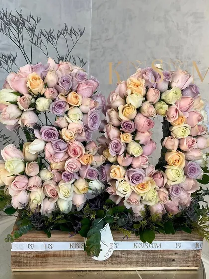 Celebrating a milestone 80th birthday with a 'Dreamland' arrangement. These floral numbers are composed of a beautiful pastel mix of lavender, baby pink, peach, and white roses, set in our rustic wooden box.