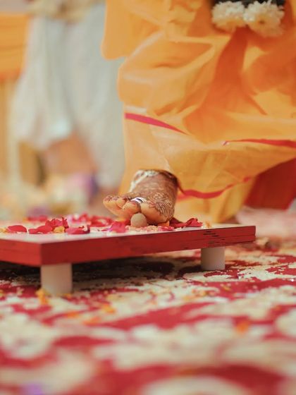 A detail shot of the bride's foot stepping onto the paat during a traditional ritual, symbolizing her entry into a new life. I capture these symbolic details with care.