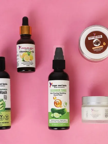 A neat flat lay arrangement of five different skincare products on a solid pink background. This helps to showcase a full routine or collection in a single, clean image.