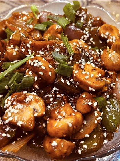 A bowl of delicious Chilli Mushroom. It has a perfect balance of spicy and savory flavors, with fresh mushrooms and crunchy vegetables.