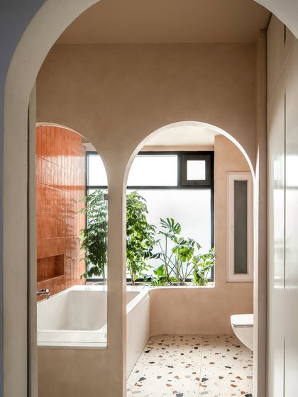 The master bathroom is a retreat designed for unwinding. Twin arches lead from the dry zone to the wet zone, where a bathtub is cradled in natural light next to a planter box that breathes life into the space.