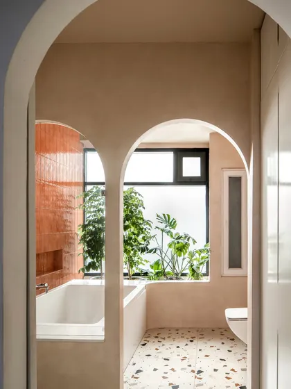 The master bathroom is a retreat designed for unwinding. Twin arches lead from the dry zone to the wet zone, where a bathtub is cradled in natural light next to a planter box that breathes life into the space.