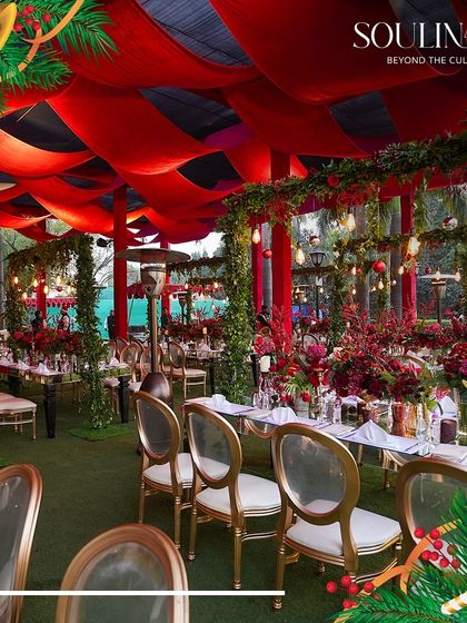 A wide view of an outdoor Christmas event, with long tables set under a canopy of red fabric and festive lights. We specialize in transforming outdoor spaces for grand holiday celebrations.