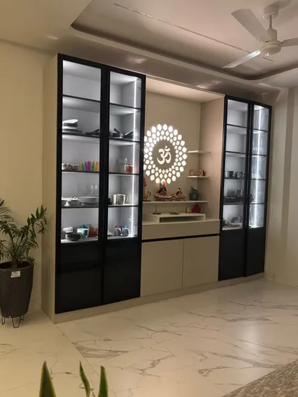 This custom unit seamlessly integrates a modern crockery display with a serene pooja mandir. It features black-framed glass shutters, internal LED lighting for the display sections, and a dedicated, beautifully lit space for worship, solving a common need in Indian homes.