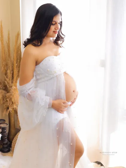 A beautiful solo portrait in a white pearl-studded gown, taken in our lifestyle setup. The natural window light creates a soft and ethereal glow.