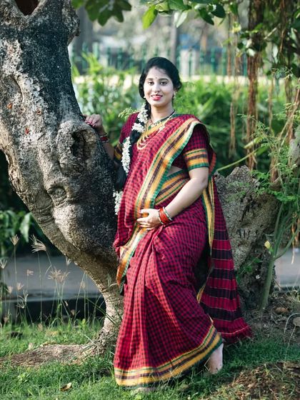 A graceful portrait in a traditional red and yellow saree. The natural setting and the classic attire combine to create a timeless and elegant maternity photo.
