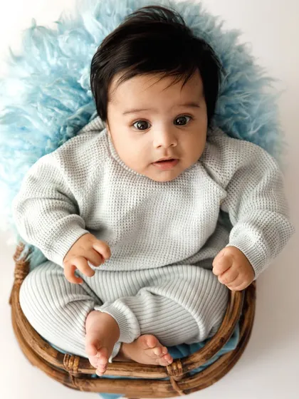 A curious little boy peeking out of a basket. At this age, babies are so alert and engaged with the world, making for adorable and expressive portraits.