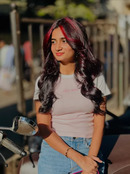 A cool, casual shot of the client enjoying her new red highlights. It's a look that's both stylish and wearable.