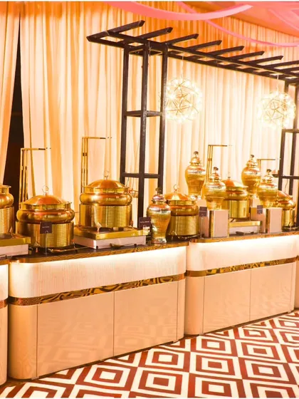 A beautiful buffet setup with elegant white and gold counters against a vibrant patterned floor. We are dedicated to making your dream occasion a reality with our flawless execution.