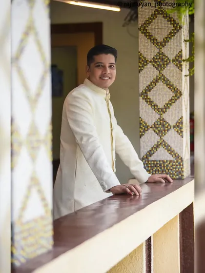 A friendly and approachable portrait of the groom. His warm smile and relaxed posture on the balcony give this photo a welcoming and happy feel.
