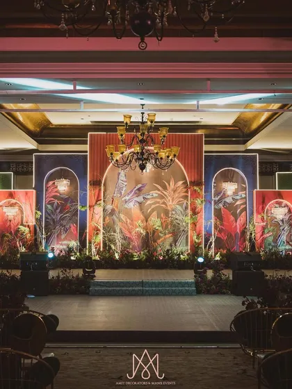This is how I bring a client's vision for a colorful, contemporary sangeet to life. The stage features multiple panels with tropical prints, framed by arches and lit to create a vibrant, layered effect.