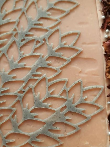 A detailed look at the custom Charcoal Rose soap. You can see the delicate stencil work, the line of dried rose petals, and the two-tone layers of pink clay and charcoal.