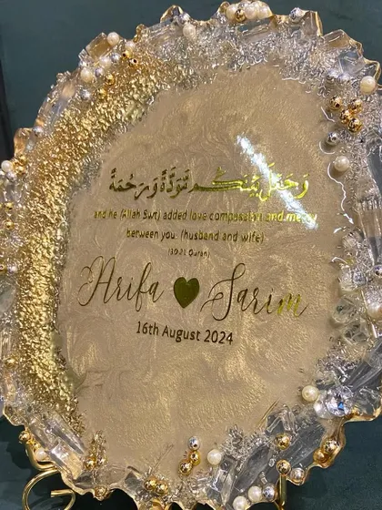 A beautiful resin engagement plaque designed to celebrate a new union. This piece features the couple's names, their special date, and a Quranic verse, all set in a shimmering gold and pearl design with a geode-style edge.