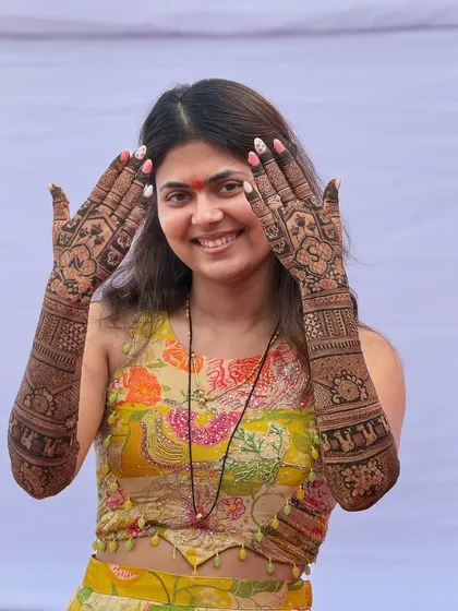 A beautiful, smiling bride showing off her intricate back-hand mehendi. Her happiness is the ultimate compliment.