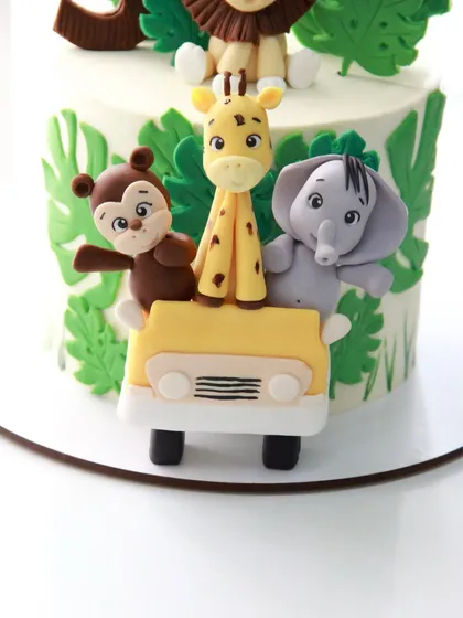 A close-up of the adorable passengers in the safari jeep: a monkey, giraffe, and elephant, all handcrafted from fondant.