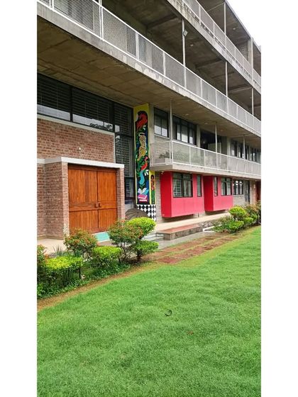 Another view of the Eklavya campus entrance, highlighting the integration of landscaping and colorful architectural elements. The building is designed to be a welcoming and stimulating environment.