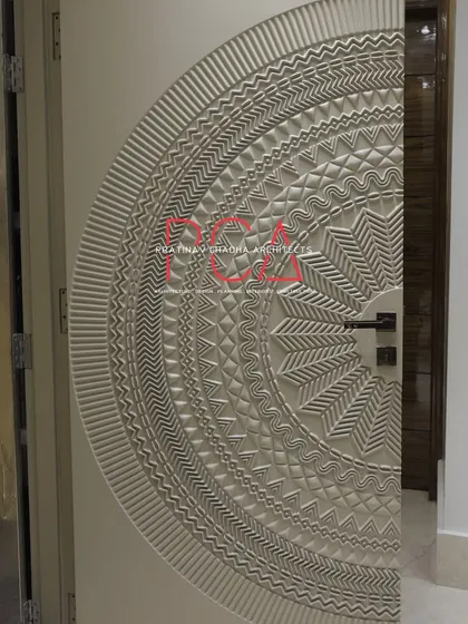 A detailed view of the main door from 'The Cursive Abode' project. This bespoke piece features an intricate, CNC-milled mandala pattern, reflecting my passion for incorporating sculptural details inspired by Indian temple architecture into modern designs.