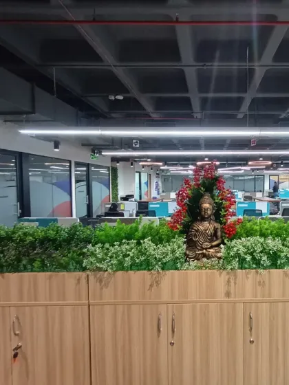 The combination of lush artificial greenery and decorative elements like this Buddha statue helps improve the overall ambiance of a corporate space.