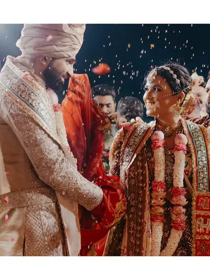 A genuine smile exchanged between the bride and groom amidst a shower of petals during their ceremony.