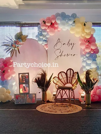 A boho-chic baby shower setup featuring a peacock chair, pampas grass, and a beautiful pastel balloon arch. This style is perfect for a trendy and relaxed celebration.