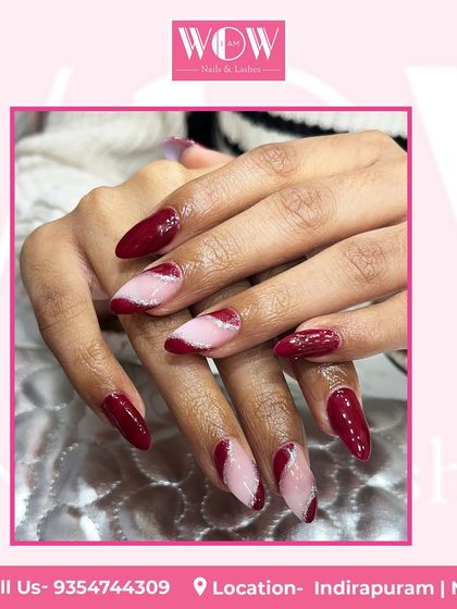 A stunning design featuring a deep red base with abstract pink and white swirls. This look on long, almond-shaped nails is both artistic and glamorous.